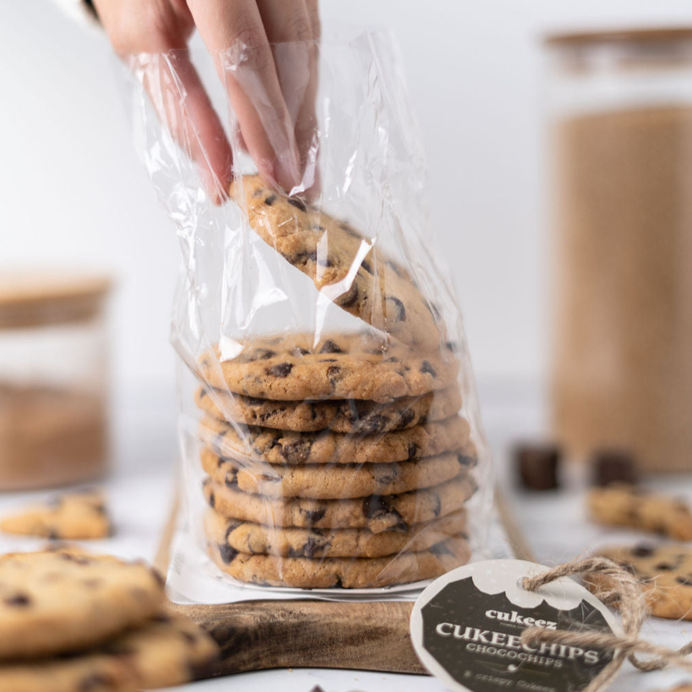 Una mano sujetando una galleta chocochips de una pila de galletas 